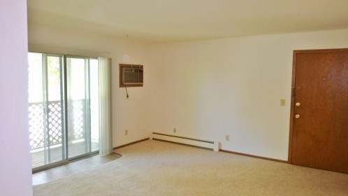 an empty living room with a door to a balcony